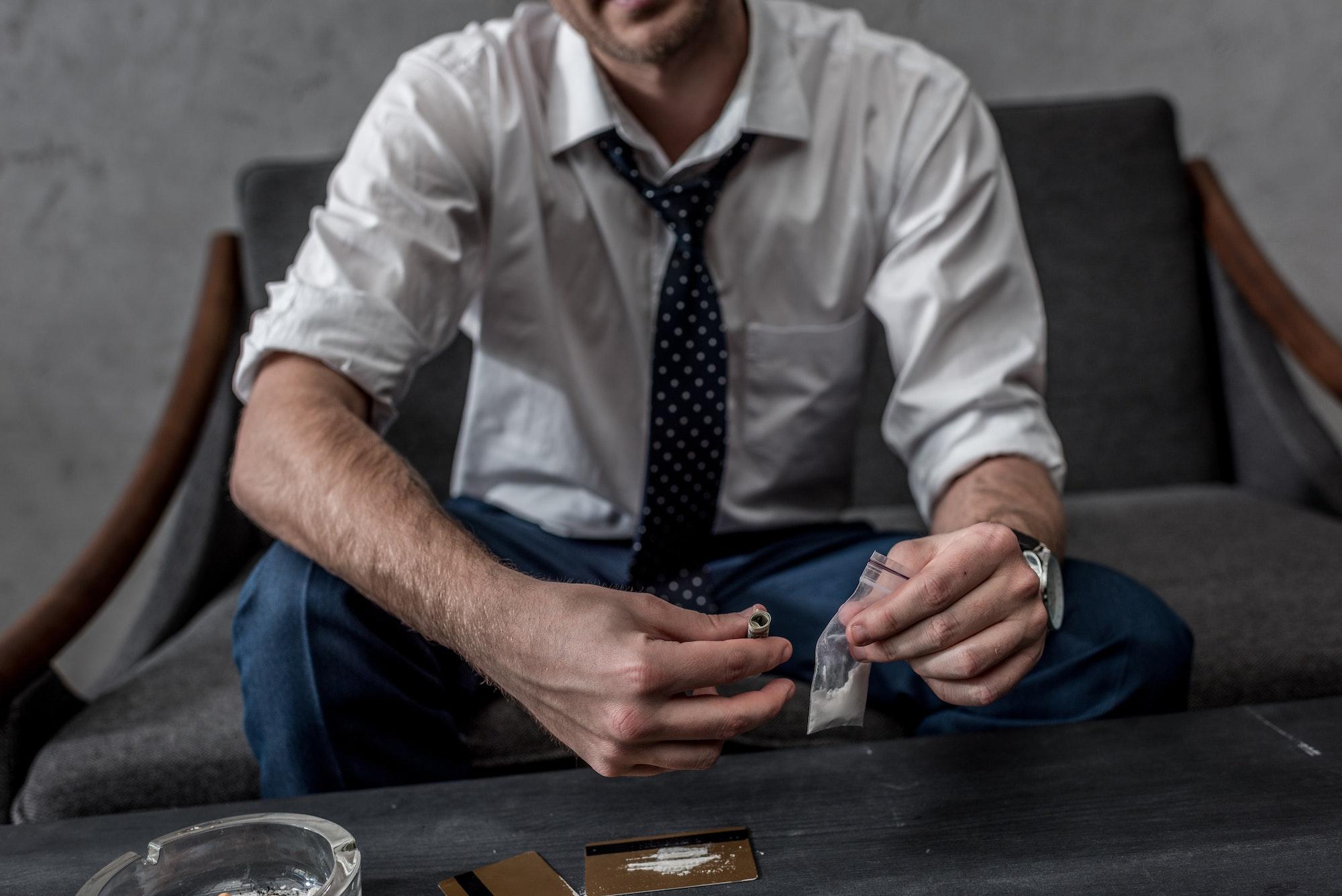 cropped shot of businessman with drug addiction holding pack of cocaine pondering if he should go to residential treatment at Saving My Tomorrow.