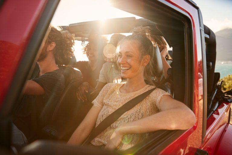 Happy millennial friends on a road trip vacation driving in an open car after achieving sobriety at Saving My Tomorrow