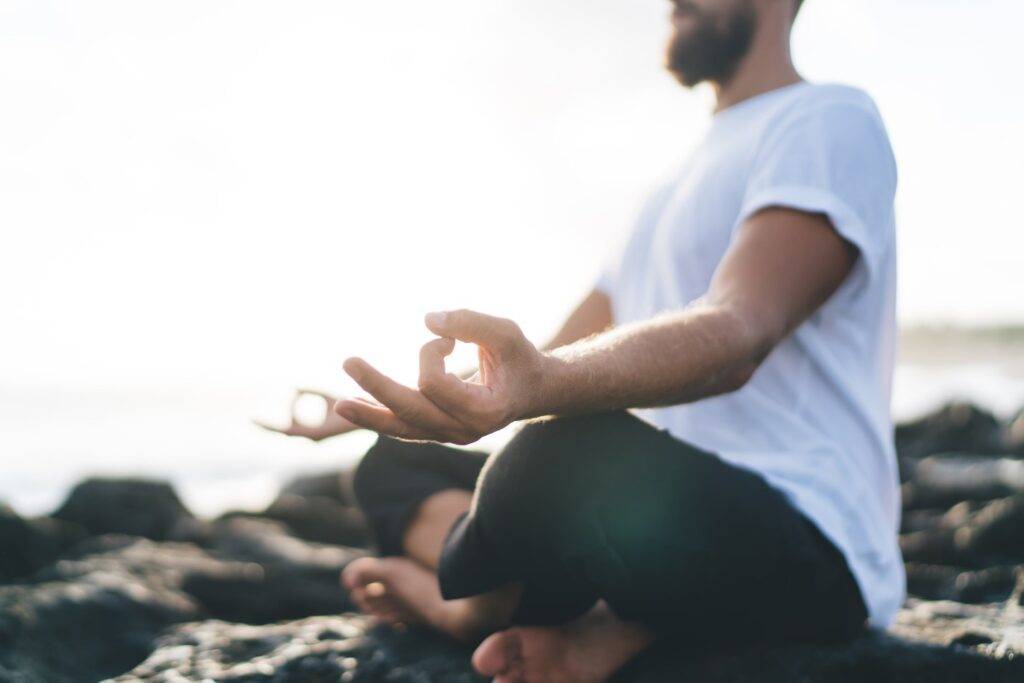 Close up of a man in mediation on the beach after completing detox.