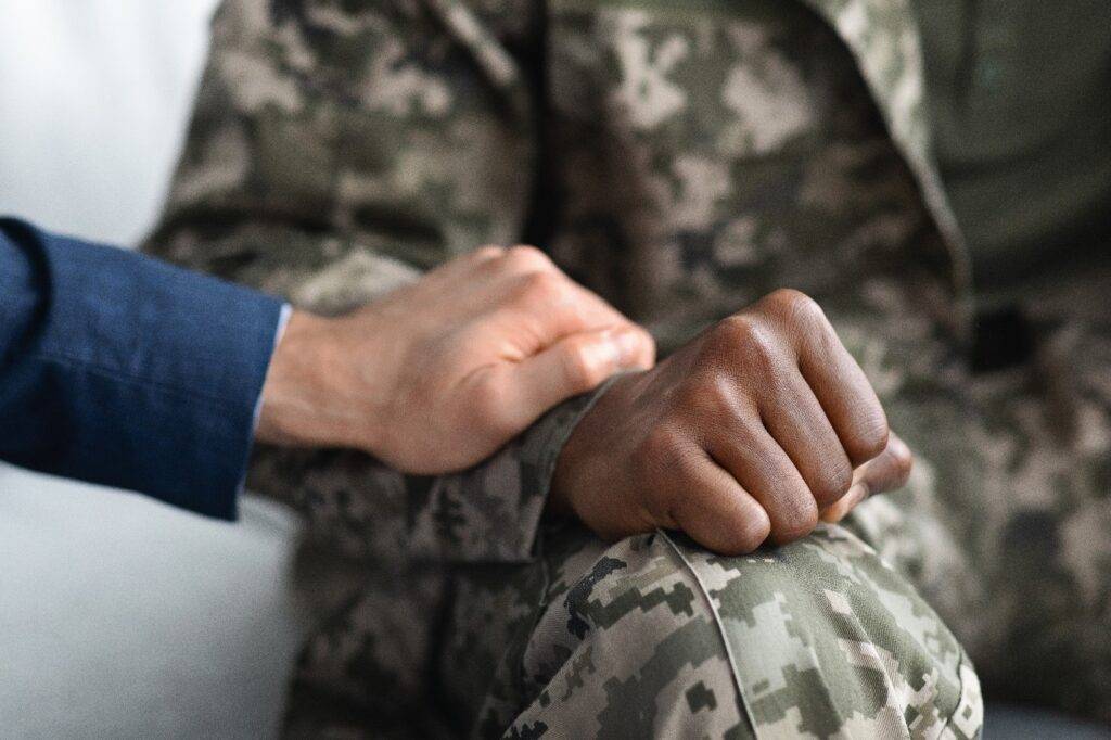 A therapist laying a comforting hand on a soldier who is suffering from substance abuse in the military