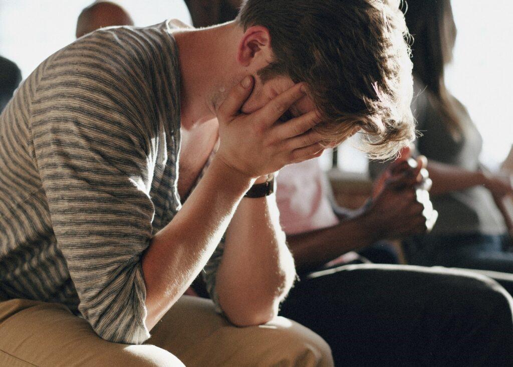 A man with his head in his hands feeling defeated after battling meth and alcohol