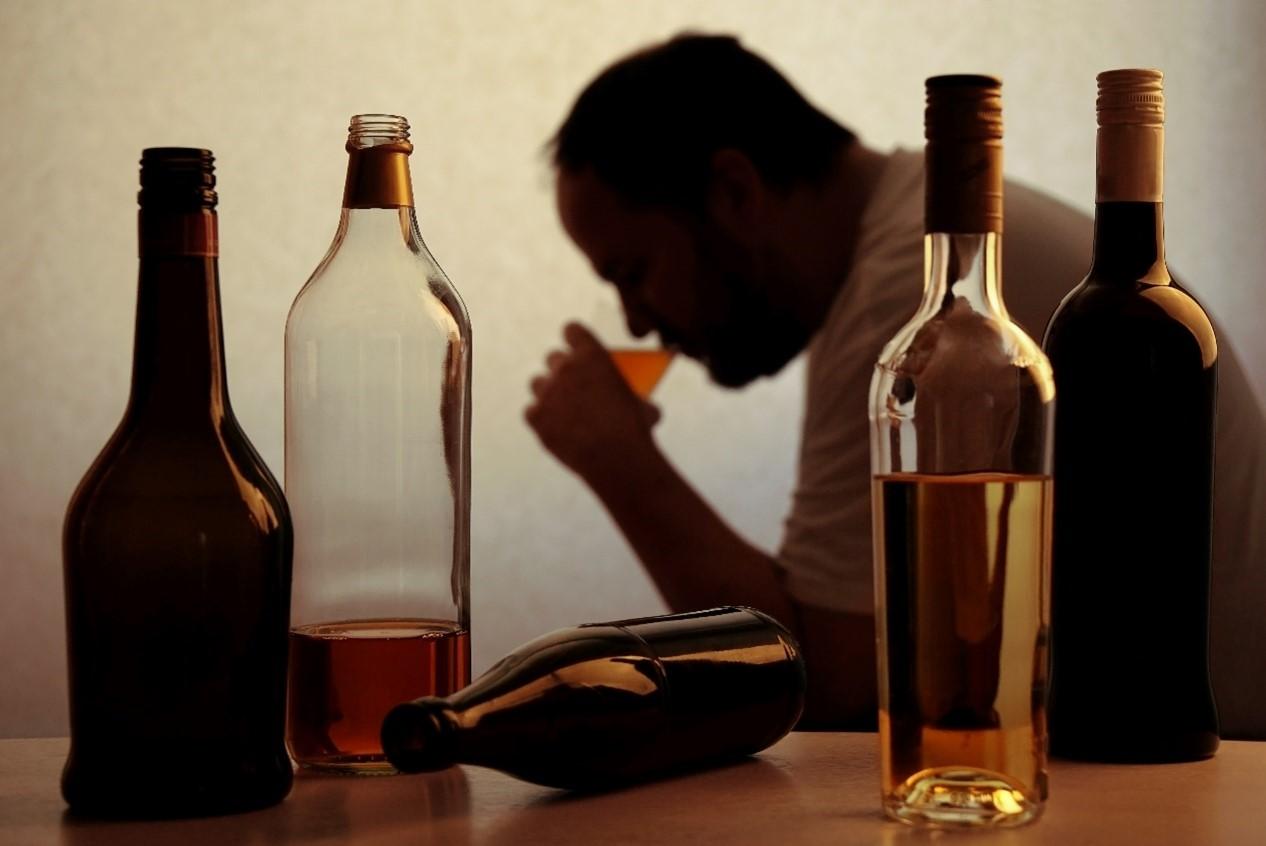 a man behind numerous alcohol bottles, as he is battling with meth and alcohol